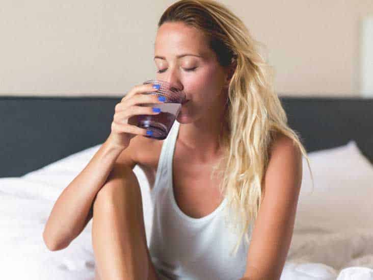 Femme buvant un verre d'eau le matin