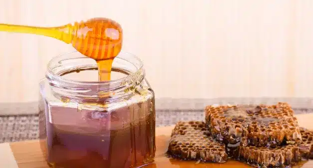 Pot de miel entouré de fleurs et d'abeilles