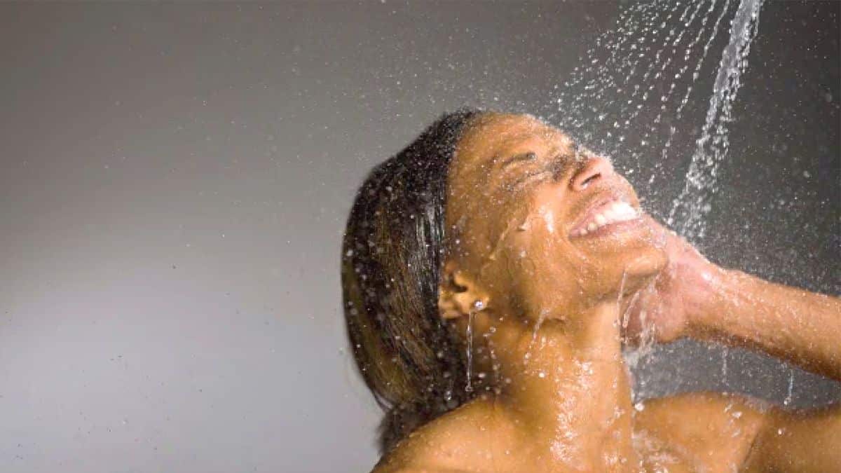 Jeune femme se lavant le visage sous la douche