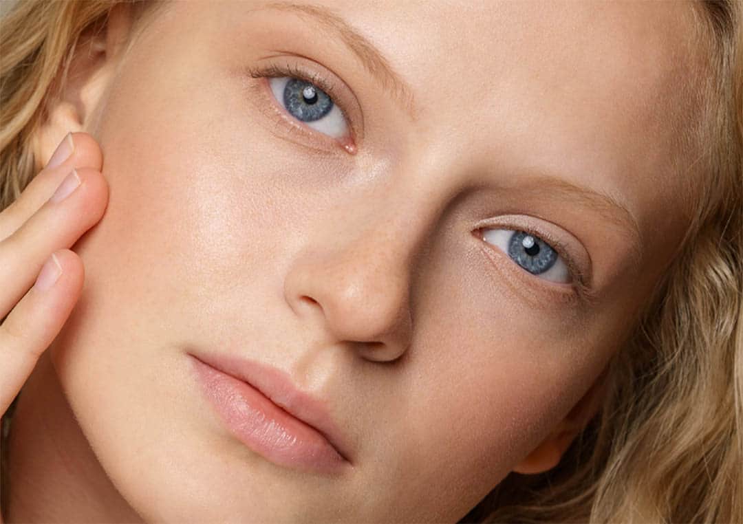 Jeune femme touchant sa joue pour illustrer la tonicité de la peau