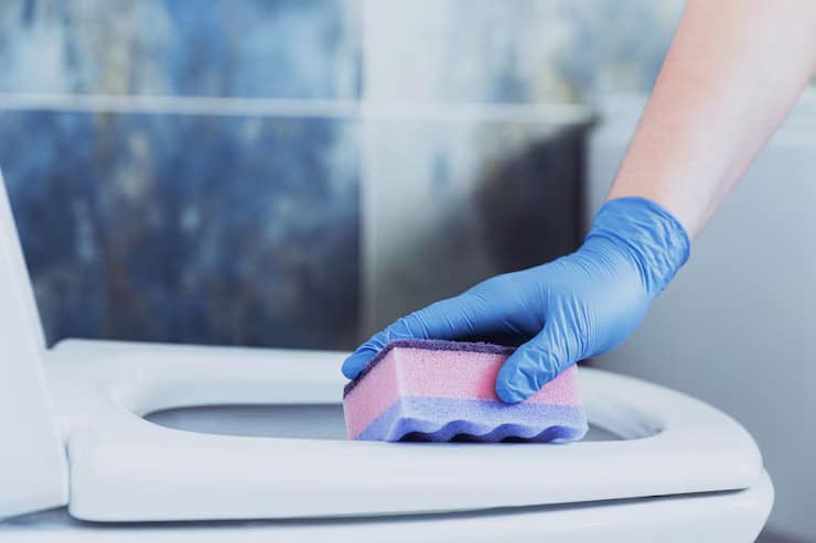 Femme nettoyant des toilettes avec des gants