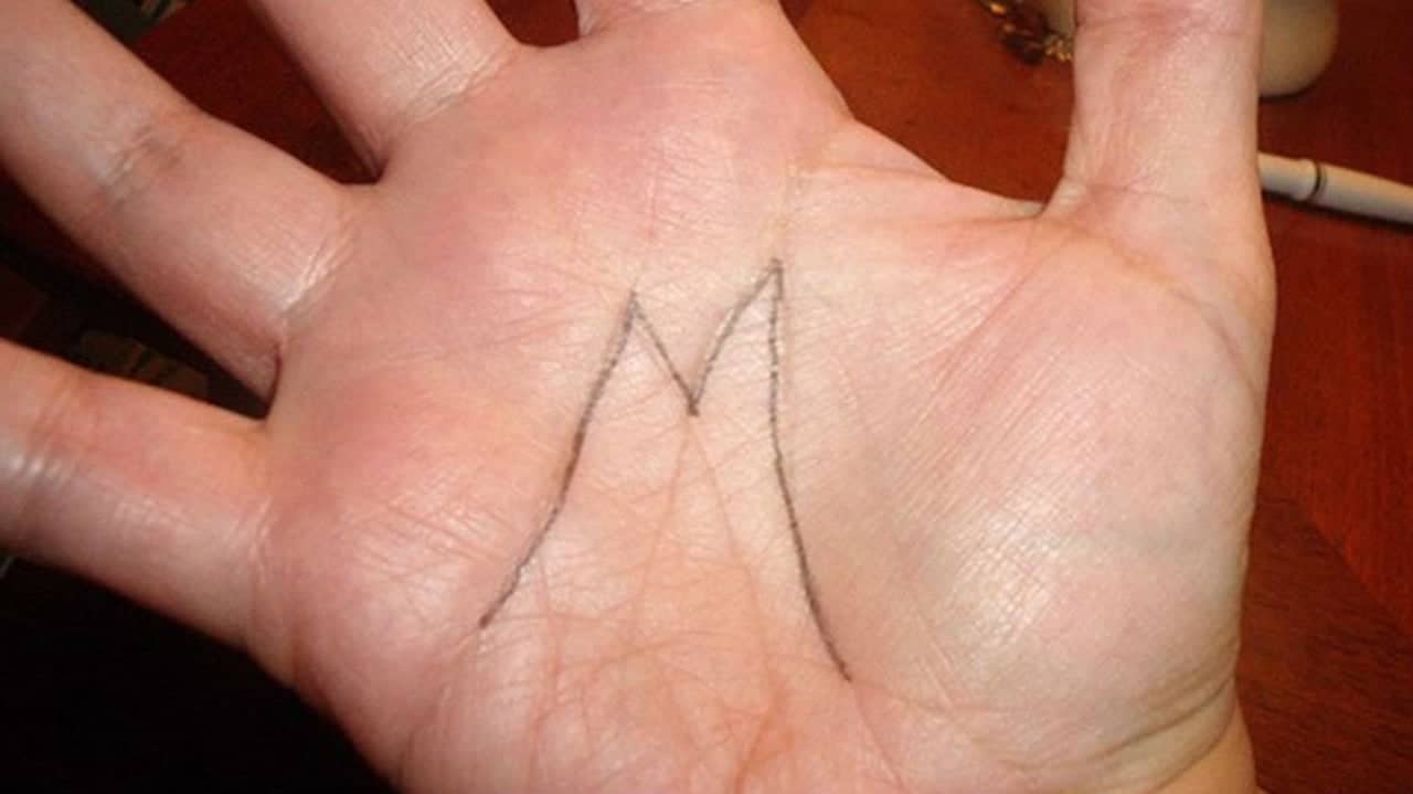 Détail d'une main présentant la lettre M