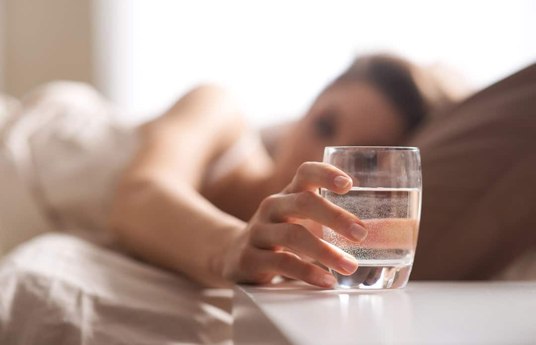 Personne buvant un verre d'eau le matin