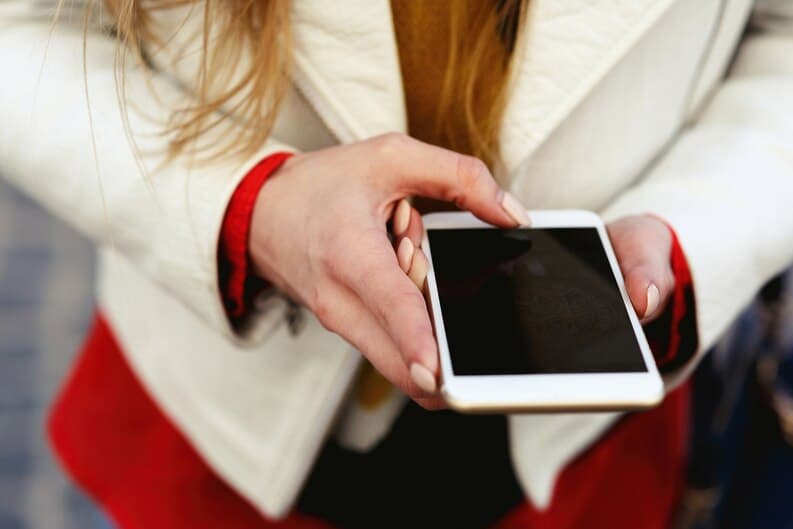 Jeune femme blonde prenant une photo avec son smartphone