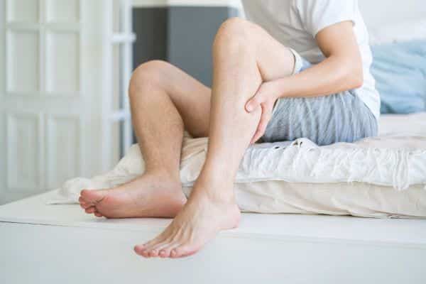 Homme se massant la jambe pour soulager une crampe