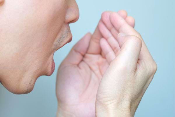 Homme vérifiant son haleine dans sa main