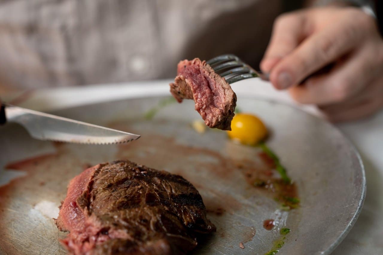 Viande saignante et œuf cru posés sur une planche en bois